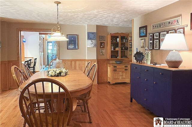 24 W 2nd St, Westfield, NY 14787 - dining area with a textured ceiling, light wood-style flooring, a wainscoted wall, and wooden walls