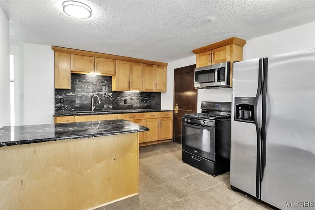 1335 James Ave, Niagara Falls, NY 14305 - kitchen with stainless steel appliances, backsplash, light brown cabinetry, dark stone countertops, and a textured ceiling