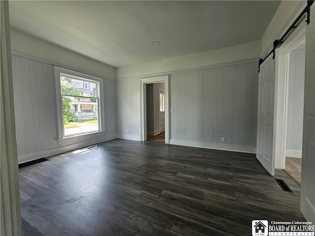901 W Henley St, Olean, NY 14760 - unfurnished bedroom featuring a barn door and dark wood-style floors