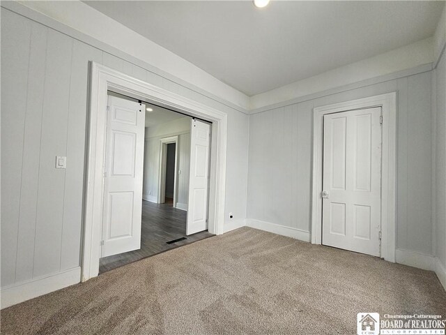 901 W Henley St, Olean, NY 14760 - unfurnished bedroom featuring carpet flooring, a decorative wall, and a barn door