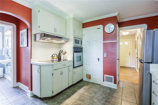 54 Covington Rd, Irondequoit, NY 14617 - kitchen featuring appliances with stainless steel finishes, under cabinet range hood, light countertops, crown molding, and arched walkways