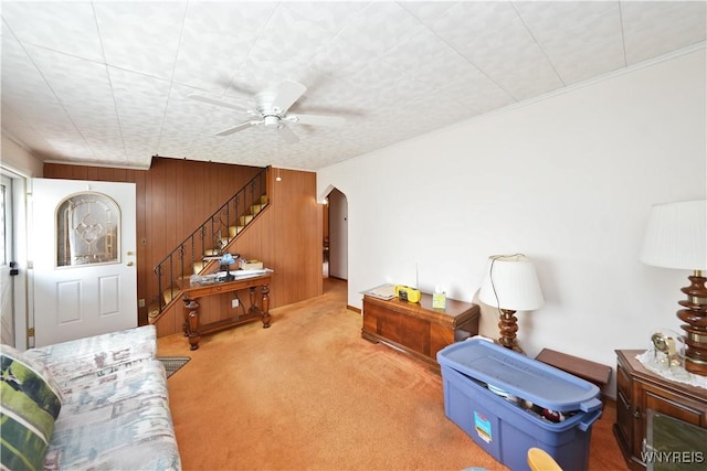 6167 N Whitham Dr, Niagara, NY 14304 - carpeted living room featuring stairs, arched walkways, a ceiling fan, and wood walls