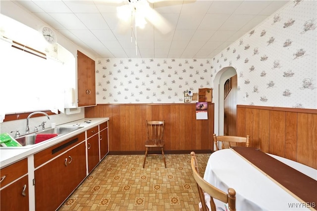 6167 N Whitham Dr, Niagara, NY 14304 - kitchen with a wainscoted wall, arched walkways, light countertops, wooden walls, and light floors
