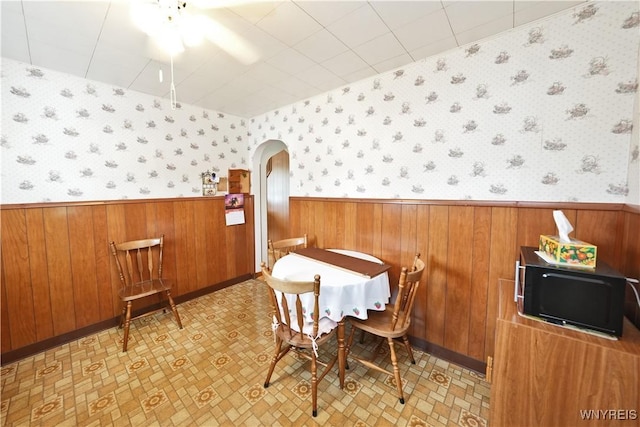 6167 N Whitham Dr, Niagara, NY 14304 - dining room with wallpapered walls, wainscoting, arched walkways, ceiling fan, and wood walls
