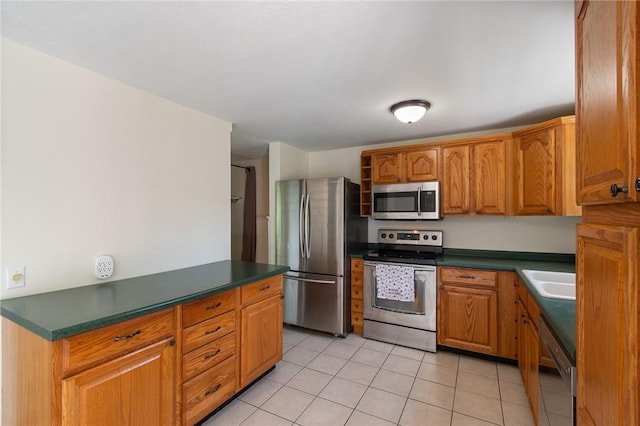 1535 Bluestem Ct, Walworth, NY 14568 - kitchen with appliances with stainless steel finishes, light tile patterned flooring, dark countertops, and brown cabinetry