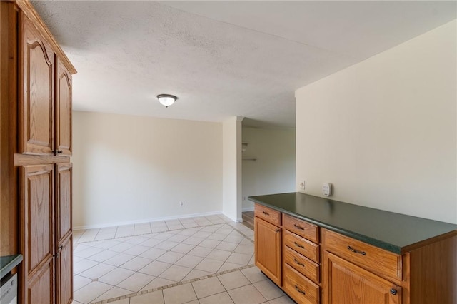 1535 Bluestem Ct, Walworth, NY 14568 - kitchen featuring dark countertops, light tile patterned floors, brown cabinets, and a textured ceiling