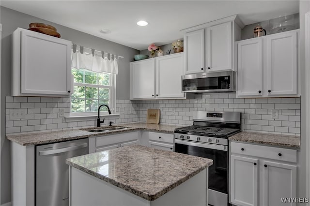 5 Scooter Ln, Hamburg, NY 14075 - kitchen with appliances with stainless steel finishes, white cabinets, backsplash, a kitchen island, and light stone countertops