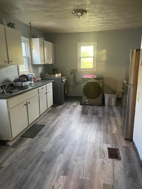 355 Champlain St Unit 353, Rochester, NY 14611 - kitchen featuring washer / dryer, freestanding refrigerator, white cabinets, dark countertops, and wood finished floors