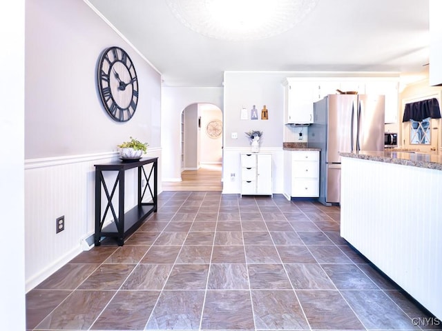 9242 Sixty Rd, Lysander, NY 13135 - kitchen featuring arched walkways, freestanding refrigerator, white cabinets, stone counters, and wainscoting