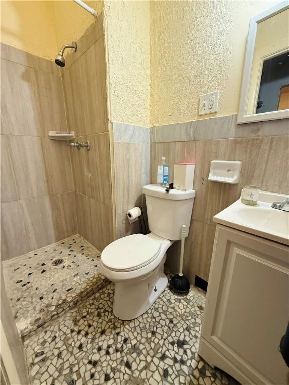 188 5th St, Rochester, NY 14605 - bathroom featuring tiled shower, vanity, a textured wall, and wainscoting