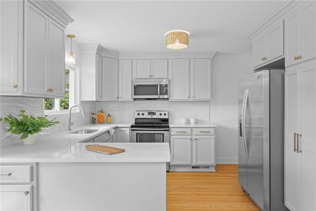 33 W Crest Dr, Gates, NY 14606 - kitchen with stainless steel appliances, light countertops, a peninsula, backsplash, and light wood finished floors