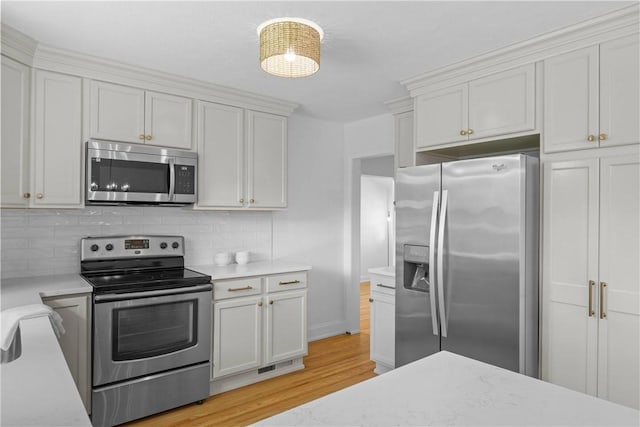 33 W Crest Dr, Gates, NY 14606 - kitchen featuring appliances with stainless steel finishes, light wood-type flooring, tasteful backsplash, white cabinets, and light stone counters
