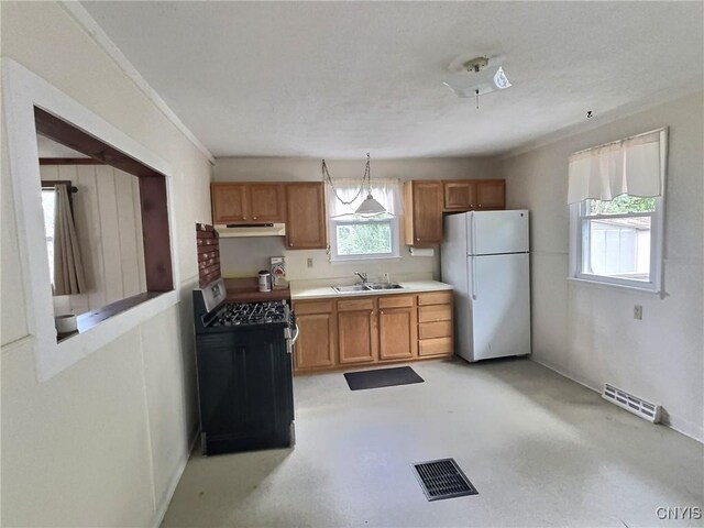 313 Chestnut St, Oswego, NY 13126 - kitchen with freestanding refrigerator, under cabinet range hood, gas stove, light countertops, and brown cabinetry