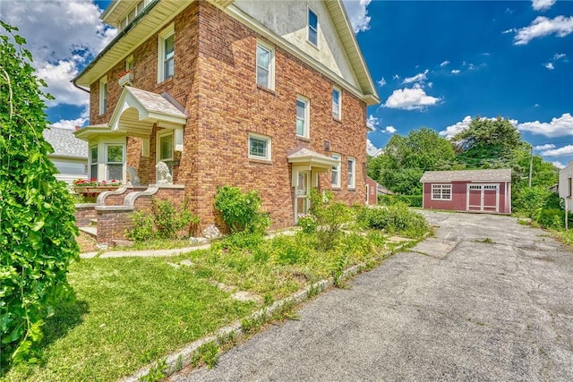 112 Isabelle St, Rochester, NY 14606 - view of side of property with a storage unit, brick siding, stucco siding, and asphalt driveway