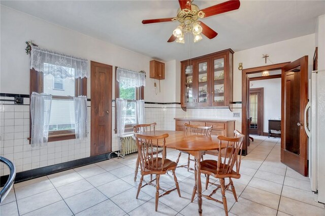 112 Isabelle St, Rochester, NY 14606 - dining room featuring tile walls, light tile patterned flooring, a ceiling fan, a wainscoted wall, and radiator