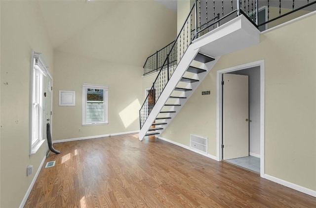 1162 Draper Ave, Elmira, NY 14905 - unfurnished living room featuring high vaulted ceiling, wood finished floors, and stairs