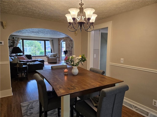 211 Steko Ave, Rochester, NY 14615 - dining area featuring arched walkways, a chandelier, dark wood-style flooring, and a textured ceiling