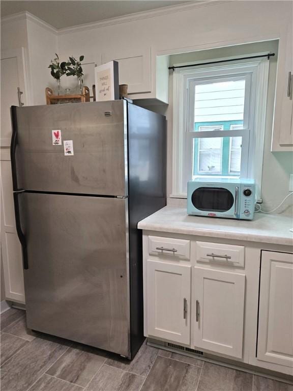 211 Steko Ave, Rochester, NY 14615 - kitchen with freestanding refrigerator, white cabinetry, ornamental molding, light countertops, and light wood-style floors