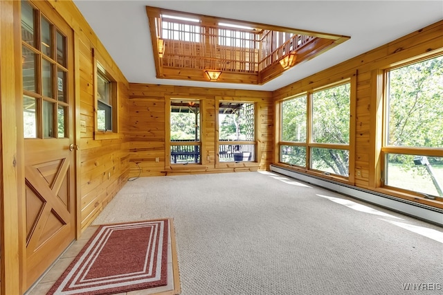 1520 Davis Rd, Aurora, NY 14170 - unfurnished living room featuring a tray ceiling, healthy amount of natural light, baseboard heating, light colored carpet, and wood walls