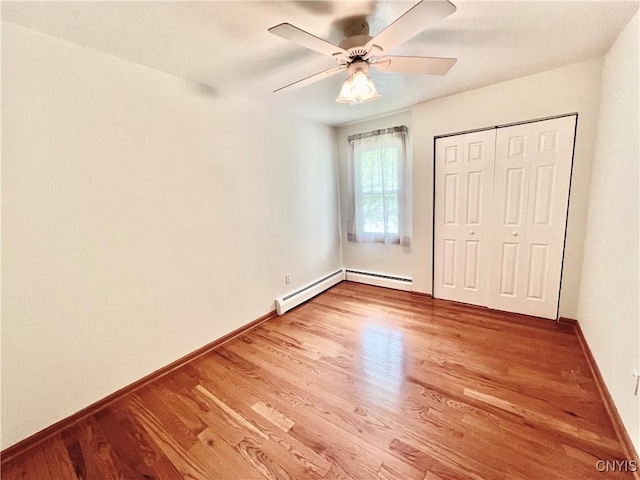 23 Burden Dr, Oswego, NY 13126 - unfurnished bedroom with wood finished floors, a baseboard heating unit, a closet, and a ceiling fan