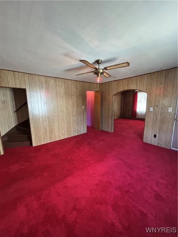 83 Felton St, North Tonawanda, NY 14120 - unfurnished room featuring arched walkways, wooden walls, dark colored carpet, and a ceiling fan