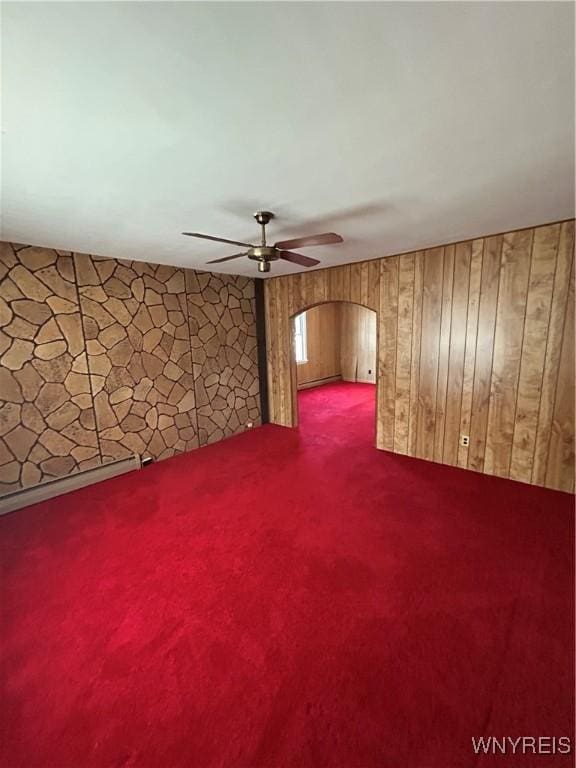 83 Felton St, North Tonawanda, NY 14120 - carpeted empty room with a ceiling fan, arched walkways, a baseboard radiator, and wood walls