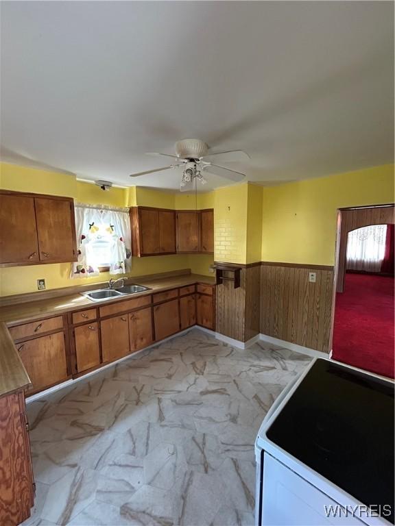 83 Felton St, North Tonawanda, NY 14120 - kitchen with white range with electric stovetop, light marble finish floors, a wainscoted wall, plenty of natural light, and brown cabinetry