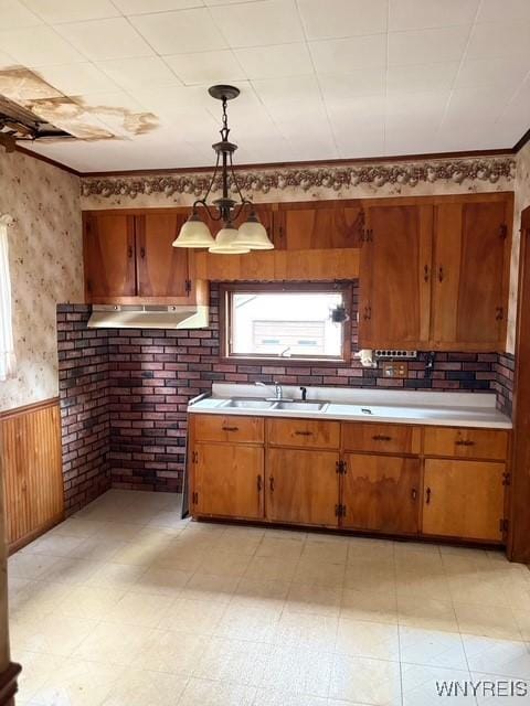 93 Mariemont Ave, Buffalo, NY 14220 - kitchen featuring wainscoting, light countertops, brown cabinets, wallpapered walls, and hanging light fixtures