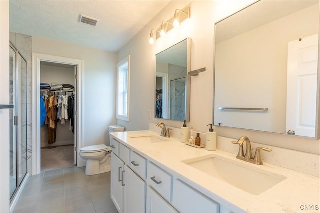 3427 Tall Tree Ln, Lysander, NY 13027 - bathroom with a walk in closet, double vanity, a shower stall, tile patterned flooring, and a textured ceiling
