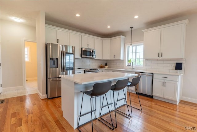 3427 Tall Tree Ln, Lysander, NY 13027 - kitchen featuring appliances with stainless steel finishes, white cabinetry, light countertops, a center island, and recessed lighting
