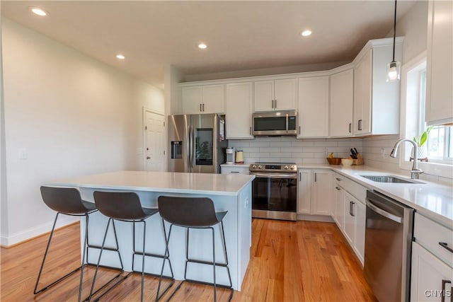 3427 Tall Tree Ln, Lysander, NY 13027 - kitchen featuring stainless steel appliances, a kitchen island, a breakfast bar, backsplash, and white cabinetry