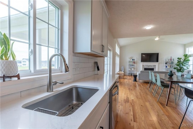 3427 Tall Tree Ln, Lysander, NY 13027 - kitchen featuring healthy amount of natural light, stainless steel dishwasher, light countertops, light wood-type flooring, and vaulted ceiling
