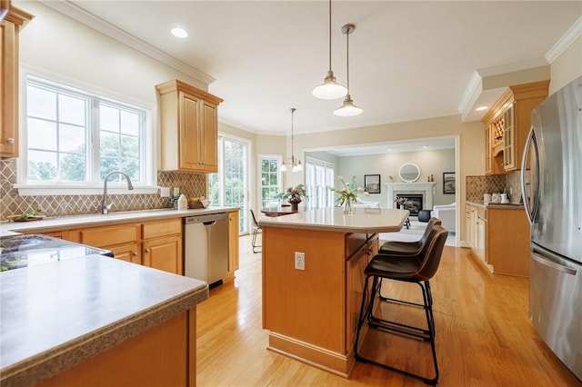 6915 Proximity Ln, Victor, NY 14564 - kitchen with appliances with stainless steel finishes, a center island, light wood finished floors, backsplash, and a fireplace