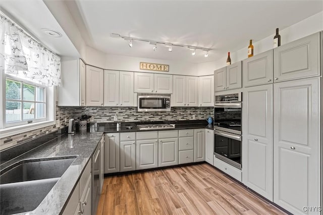 331 Hickory Ln, Hastings, NY 13036 - kitchen featuring appliances with stainless steel finishes, decorative backsplash, light wood-style floors, gray cabinetry, and dark stone counters