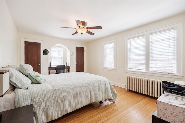 108 Iroquois St, Rochester, NY 14609 - bedroom featuring radiator, multiple windows, arched walkways, and light wood finished floors