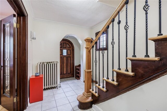 108 Iroquois St, Rochester, NY 14609 - foyer featuring radiator heating unit, arched walkways, tile patterned floors, stairway, and ornamental molding