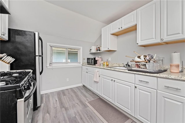 1084 Plymouth Ave S, Rochester, NY 14608 - kitchen featuring stainless steel appliances, white cabinets, light wood-style flooring, lofted ceiling, and wall chimney range hood