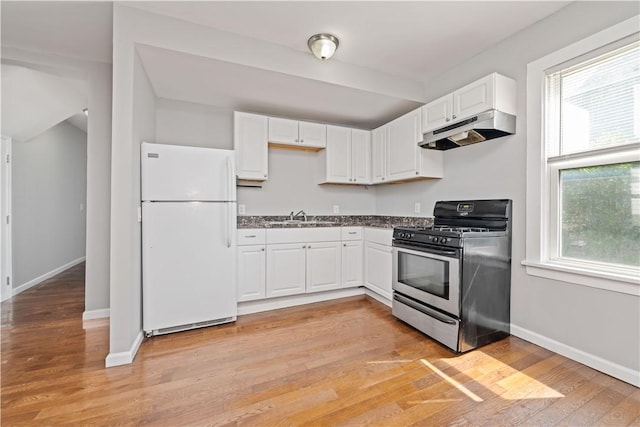 1084 Plymouth Ave S, Rochester, NY 14608 - kitchen with freestanding refrigerator, stainless steel range with gas stovetop, under cabinet range hood, white cabinets, and plenty of natural light
