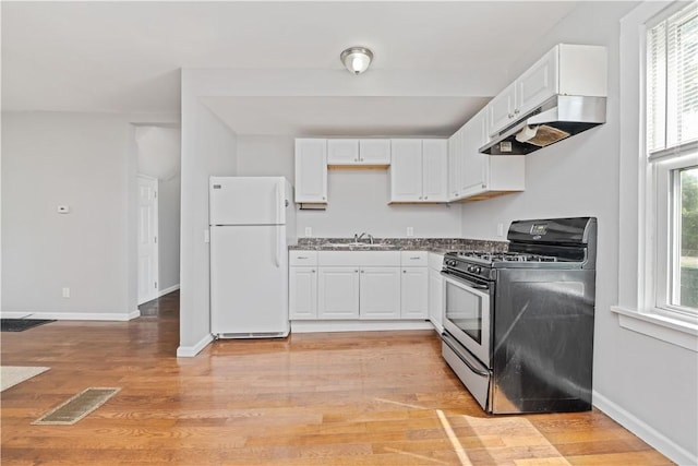 1084 Plymouth Ave S, Rochester, NY 14608 - kitchen featuring freestanding refrigerator, stainless steel gas range, under cabinet range hood, white cabinetry, and light wood-style flooring