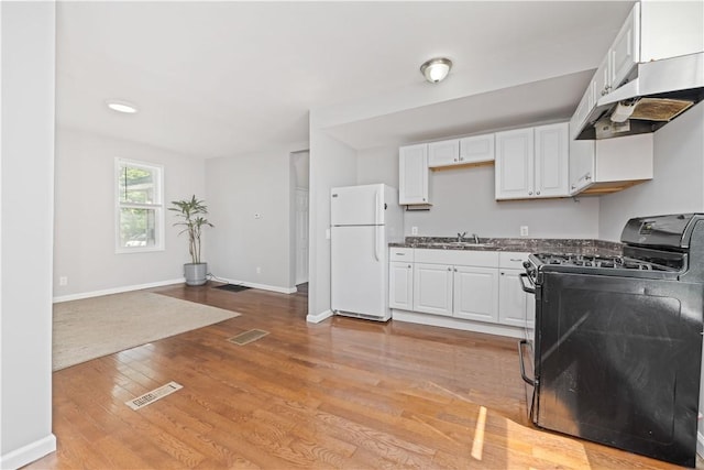 1084 Plymouth Ave S, Rochester, NY 14608 - kitchen with black range with gas cooktop, freestanding refrigerator, under cabinet range hood, white cabinets, and light wood-type flooring