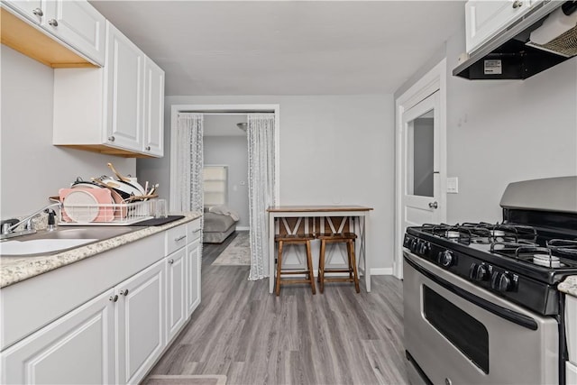 1084 Plymouth Ave S, Rochester, NY 14608 - kitchen with gas stove, range hood, white cabinets, light countertops, and light wood-style flooring