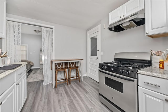 1084 Plymouth Ave S, Rochester, NY 14608 - kitchen featuring stainless steel gas stove, under cabinet range hood, light wood-style floors, white cabinetry, and light stone counters