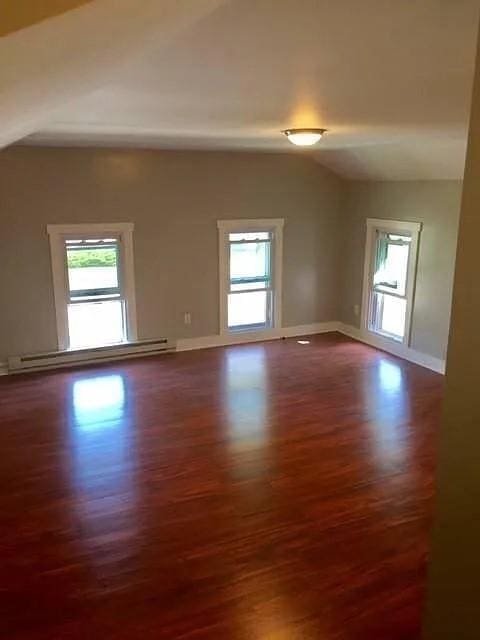 1369 Pittsford Mendon Rd, Mendon, NY 14506 - empty room with a baseboard heating unit, wood finished floors, healthy amount of natural light, and vaulted ceiling