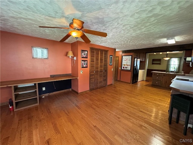 237 E Hamilton Ave, Sherrill, NY 13461 - unfurnished living room featuring light wood finished floors, a desk, ceiling fan, and a textured ceiling