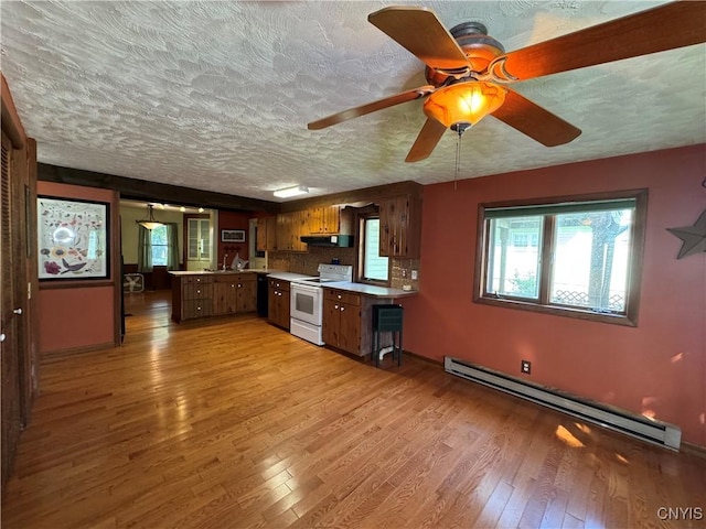 237 E Hamilton Ave, Sherrill, NY 13461 - kitchen with white electric range oven, a baseboard heating unit, a peninsula, a textured ceiling, and plenty of natural light