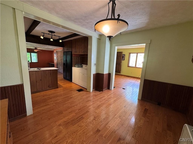 237 E Hamilton Ave, Sherrill, NY 13461 - kitchen featuring black fridge, light countertops, light wood-style flooring, beamed ceiling, and a textured ceiling