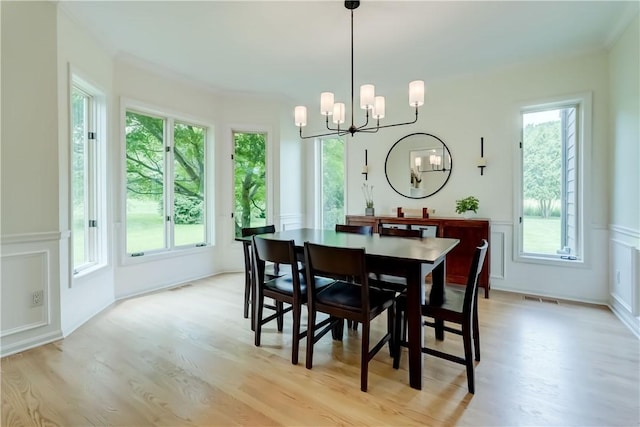 10 Muirfield Ct, Pittsford, NY 14534 - dining area with a chandelier, plenty of natural light, light wood-type flooring, a decorative wall, and wainscoting