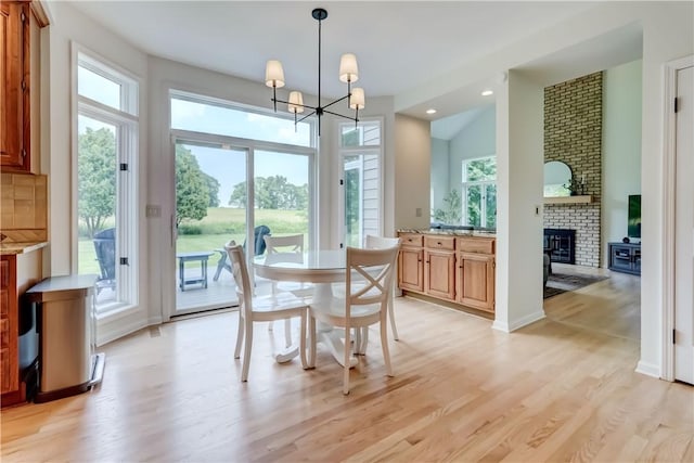 10 Muirfield Ct, Pittsford, NY 14534 - dining space featuring plenty of natural light, light wood-style flooring, a brick fireplace, a chandelier, and recessed lighting