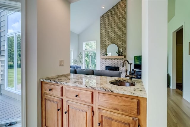 10 Muirfield Ct, Pittsford, NY 14534 - kitchen featuring a fireplace, light stone countertops, high vaulted ceiling, open floor plan, and light wood finished floors