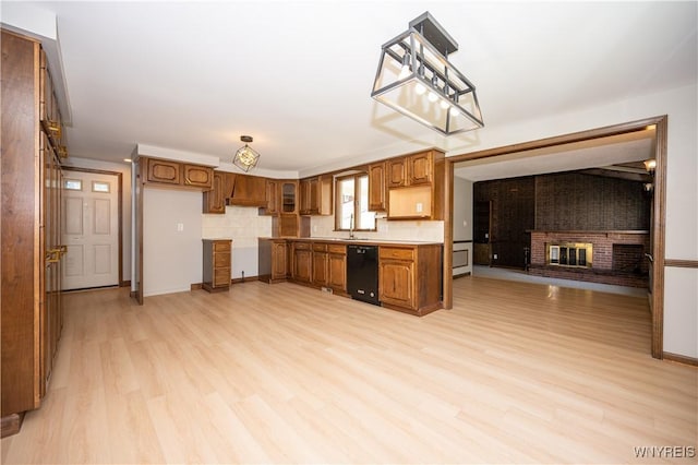 92 Schiller St, Buffalo, NY 14206 - kitchen featuring black dishwasher, a fireplace, brown cabinets, light wood-type flooring, and pendant lighting